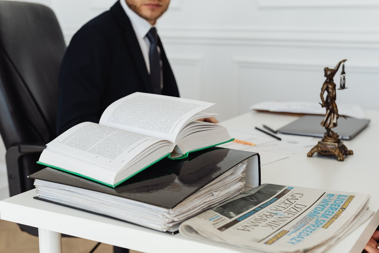 Abogada La Garriga Barcelona. A lawyer sitting at a desk with legal books, documents, and a newspaper, embodying professionalism.
