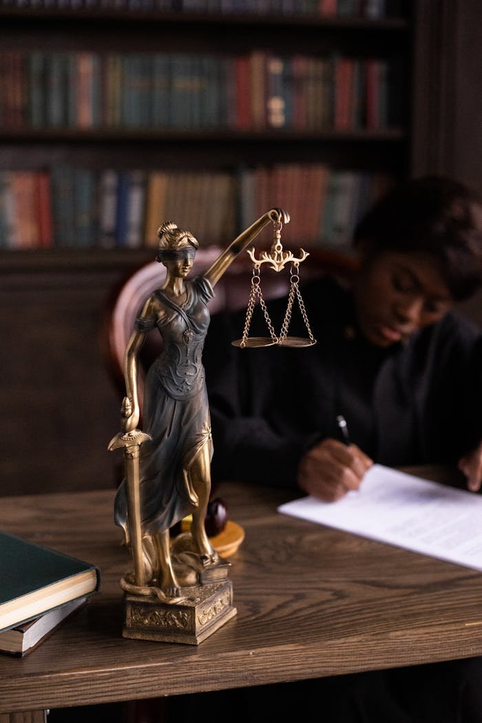 Servicios legales en La Garriga. Close-up of Lady Justice figurine on a lawyers desk with books and documents.