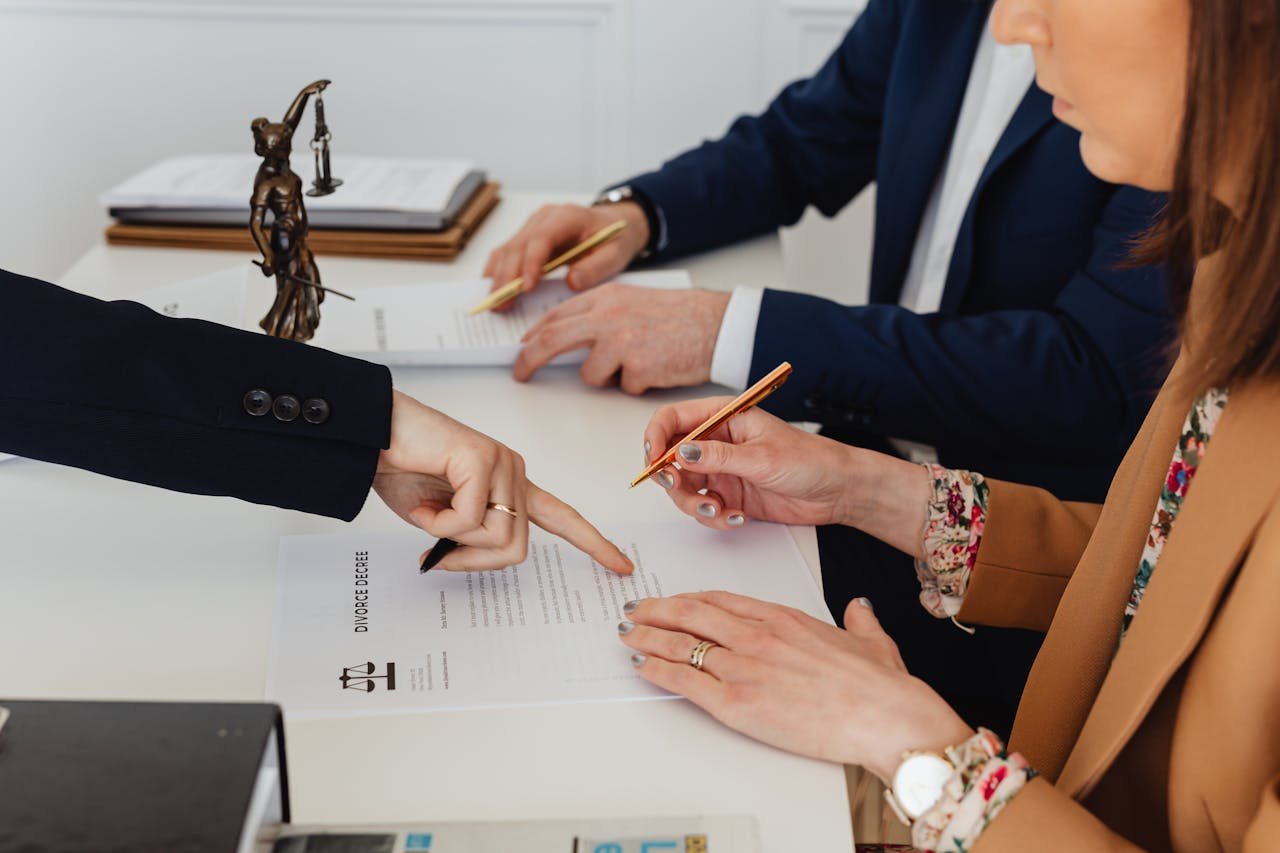 Servicios legales en La Garriga. Hands signing a divorce decree, with a justice statue nearby, symbolizing legal proceedings.